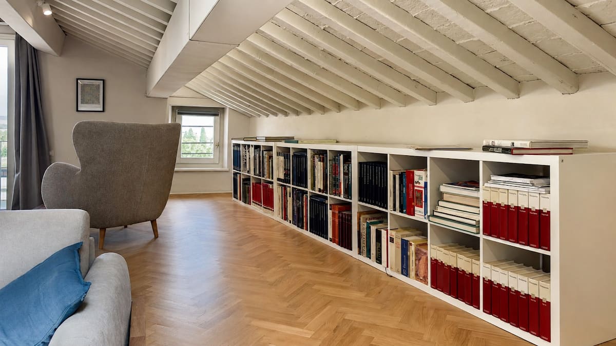 Bookshelves and reading chair beneath the timber beams of Tower View Sky Penthouse